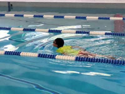 boy swimming in yellow shirt and goggles